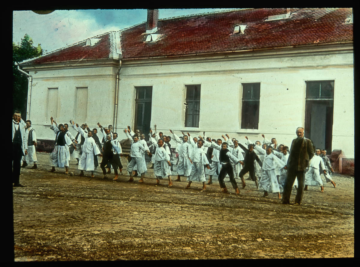 Student wearing uniforms line up and perform exercises in their physical education class. Their school is in the background.Subcarpathian Ruthenia, Czechoslovakia. | Location: Subcarpathian Ruthenia, Czechoslovakia. (Photo by Jar. Novotny/Scheufler Collection/Corbis/VCG via Getty Images)